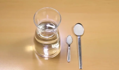 Recipiente com água, uma colher de chá com sal e uma colher de sopa de açúcar.